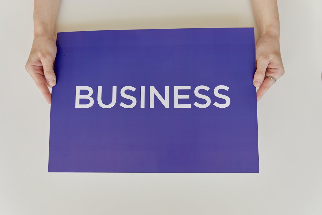 About Hands holding a purple sign with the word 'BUSINESS', symbolizing corporate concepts.